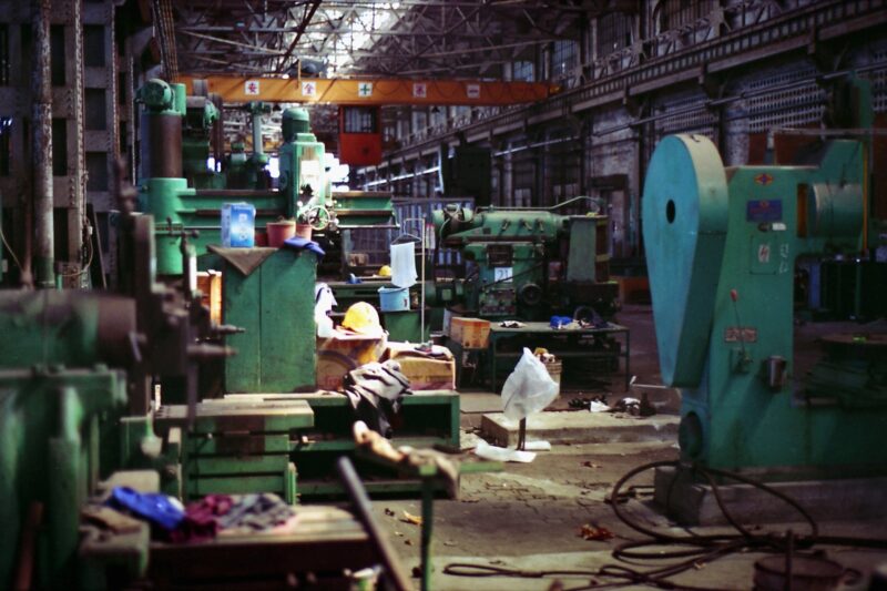 An empty factory showing machines, hardhats, and other equipment.