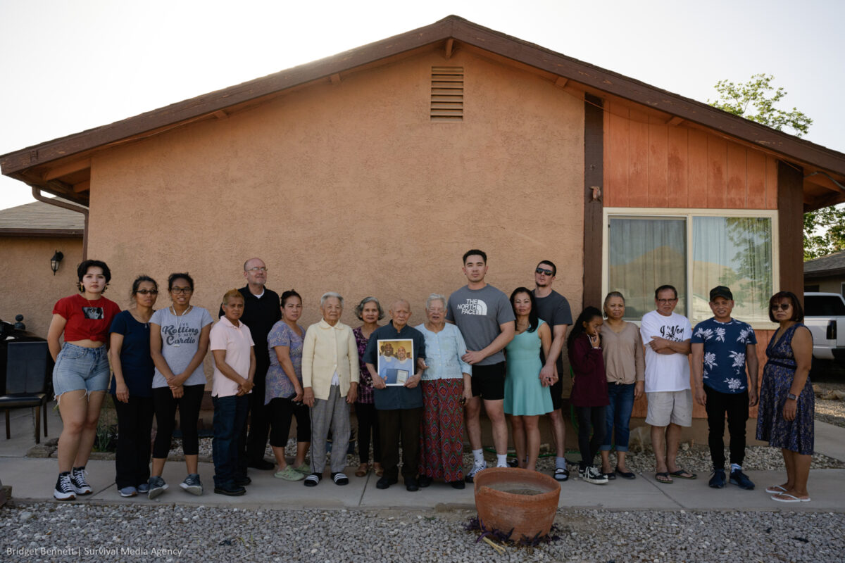 18 members of Phoeun You's family stand side by side in front of their home in Las Vegas.