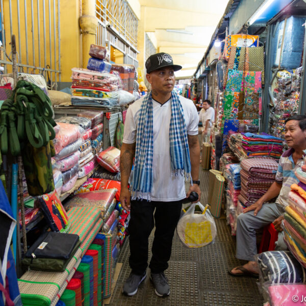 Pheoun walks through a textile bazaar in Cambodia.