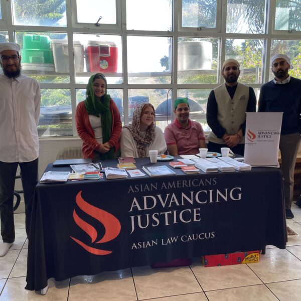 6 ALC staff members at their outreach table in a local Gurdwara, offering print resources.