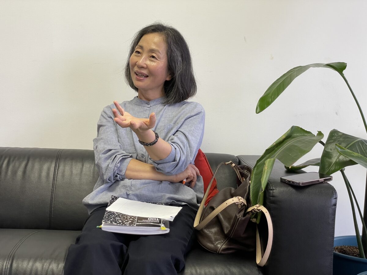 Advancing Justice-Atlanta Outreach Coordinator Kay Kang sitting on sofa, speaking animatedly.