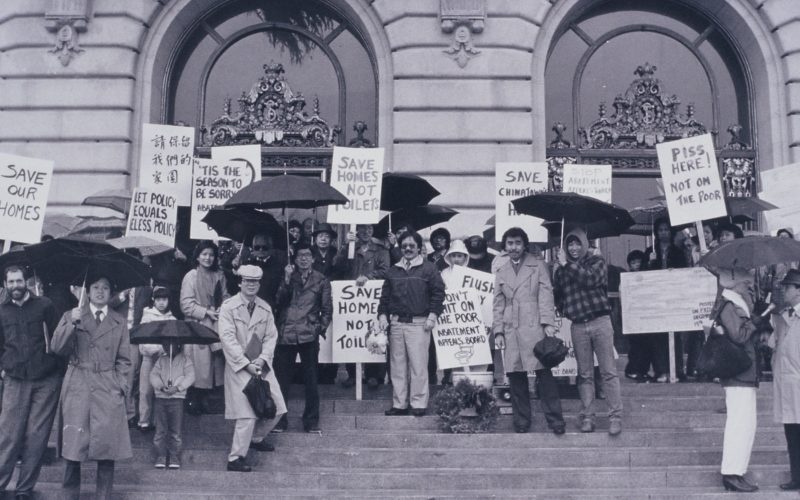 Black and white photo of protestors standing on the steps in front of San Francisco City Hall holding signs